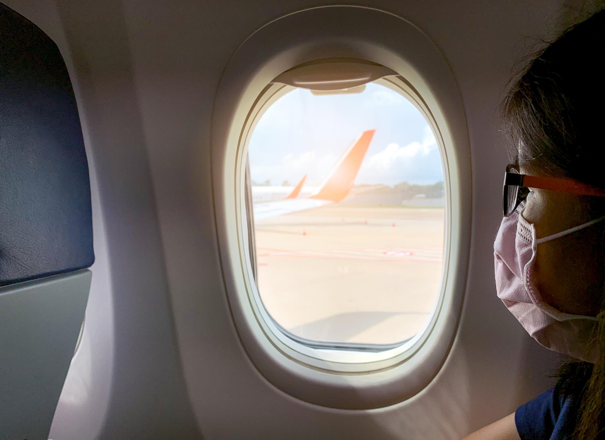 woman looking out a plane window