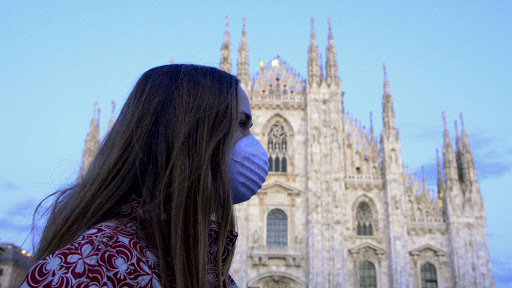 Italy, woman with mask crosses across a church