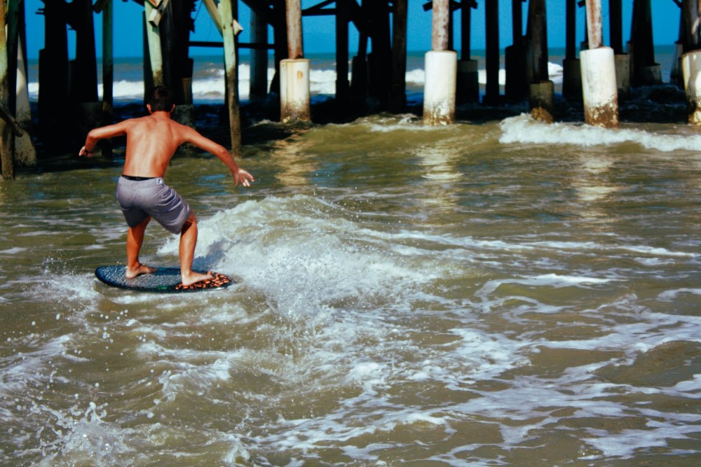 man surfing next to a pier in Southwest Florida