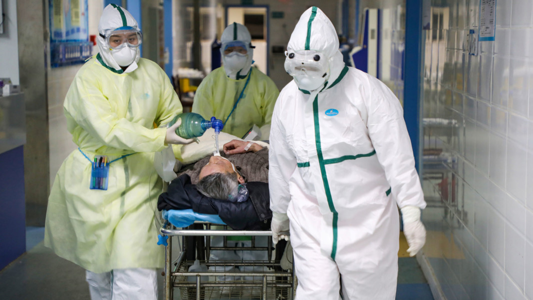 two masked nurses and patient on a gurney